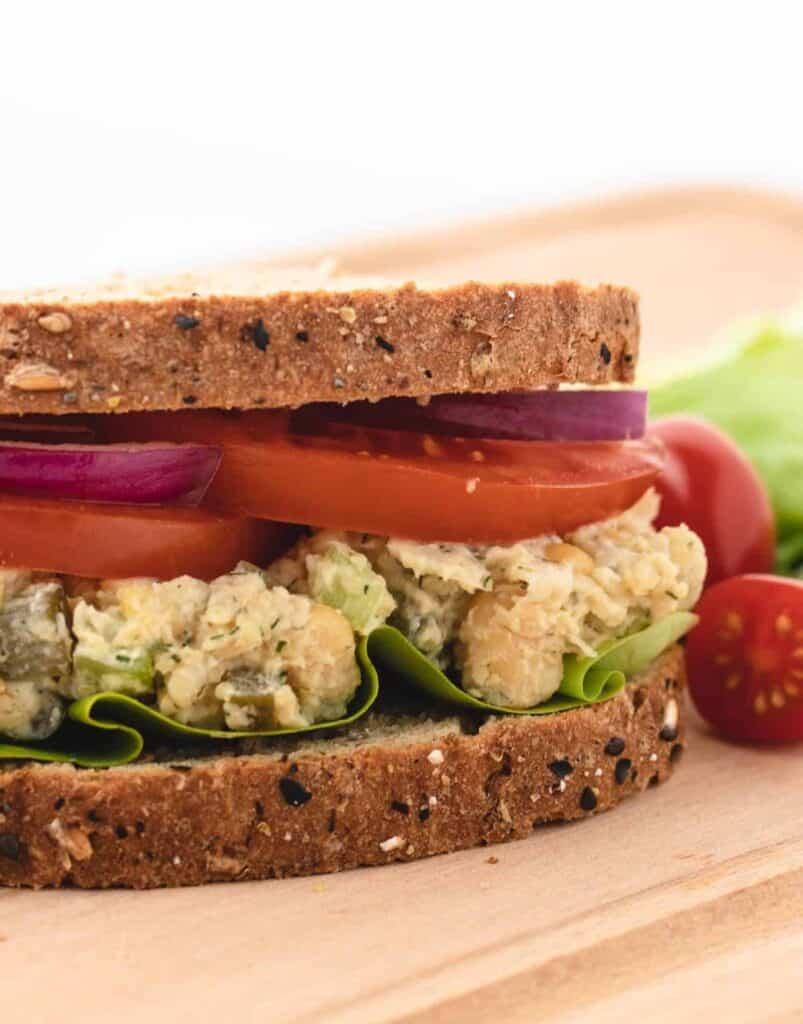 chickpea salad sandwich with sliced tomatoes and red onions
