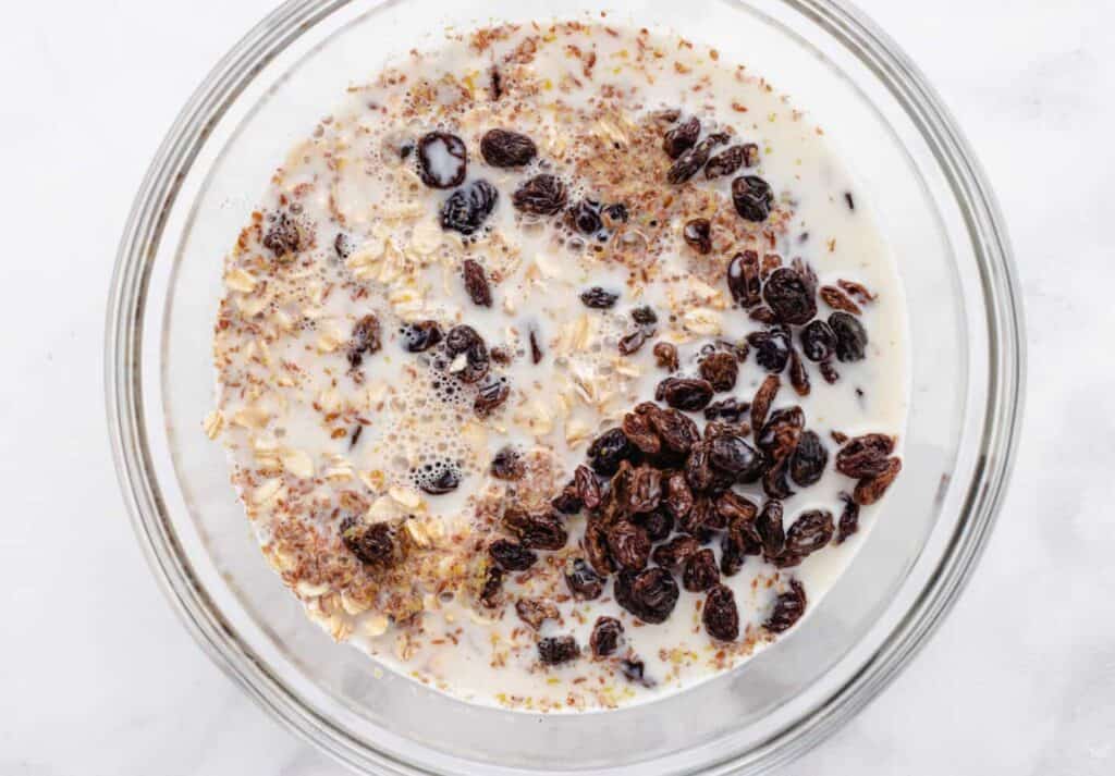 Mixed ingredients for overnight oats with raisins in a bowl.