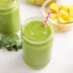 Mango smoothie without yogurt in a glass jar with a straw.