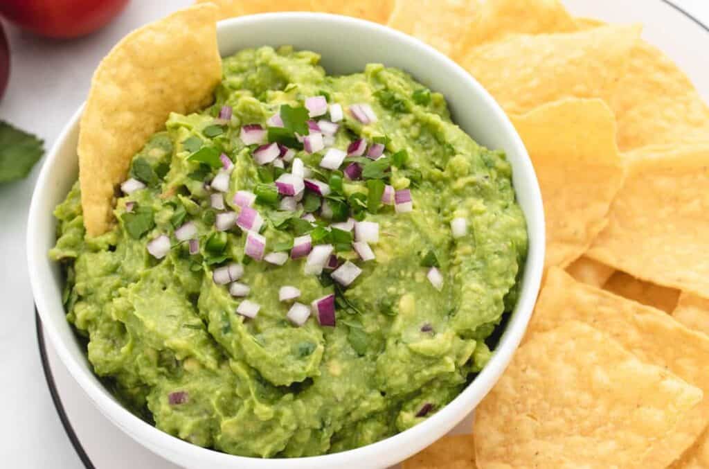 Vegan guacamole in a bowl with tortilla chips.