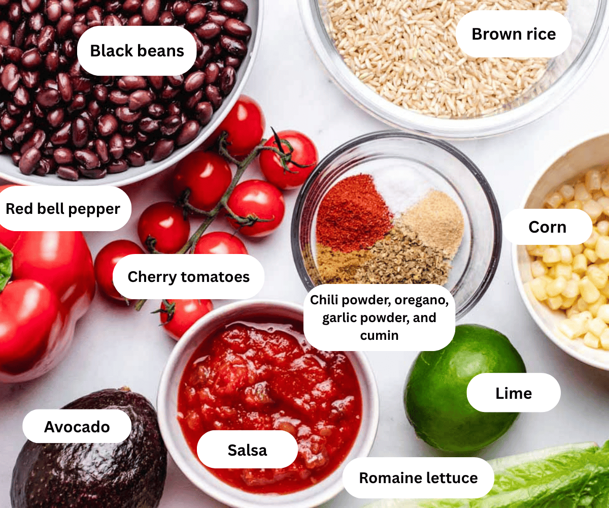 Black beans, brown rice, red bell pepper, cherry tomatoes, spices, corn, avocado, salsa, lime, and romaine lettuce on a table.