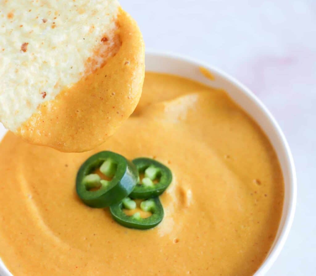 Oil-free vegan nacho cheese in a bowl with jalapeño slices.