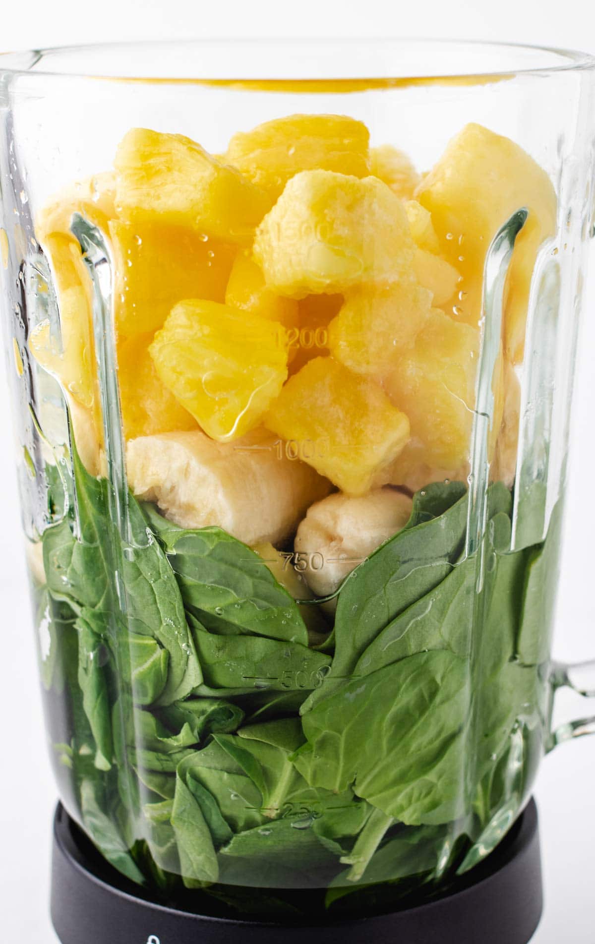 Frozen pineapple, banana, and spinach in a blender.