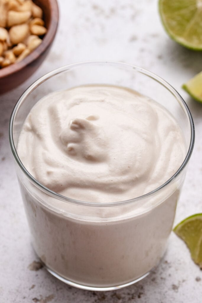 Vegan crema in a glass with limes in the background.