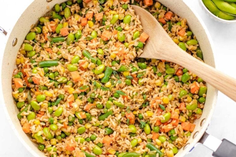 Vegan oil-free fried rice in a pan with a wooden spoon.