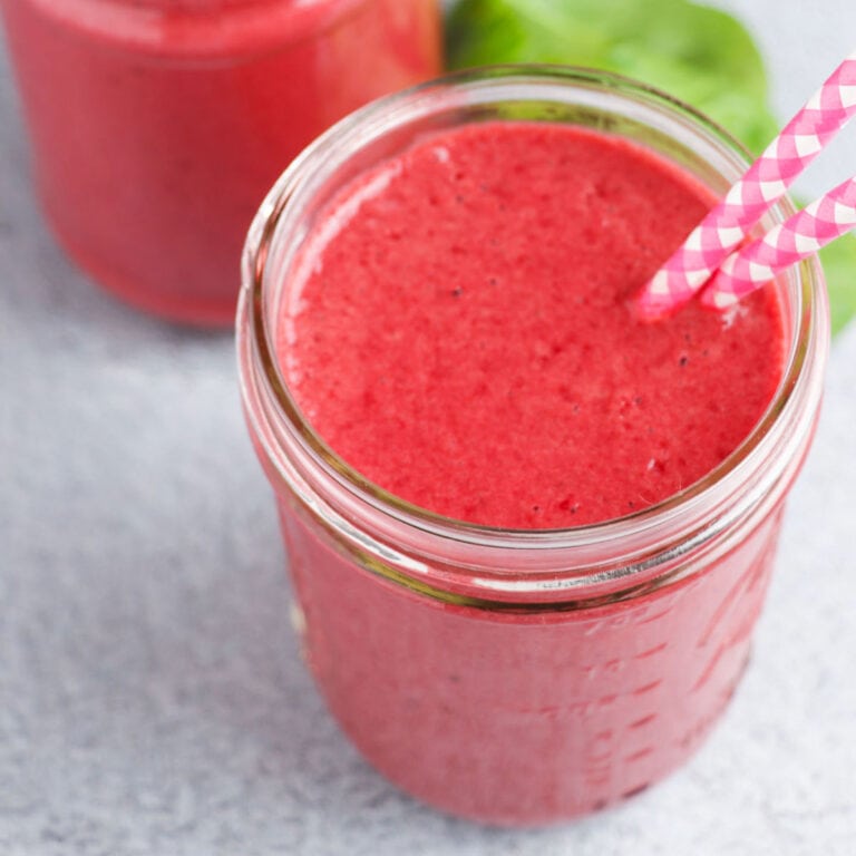 Pineapple beet smoothie in glass with straws.
