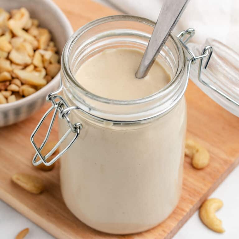 Dijon cashew salad dressing in a glass jar with a spoon.