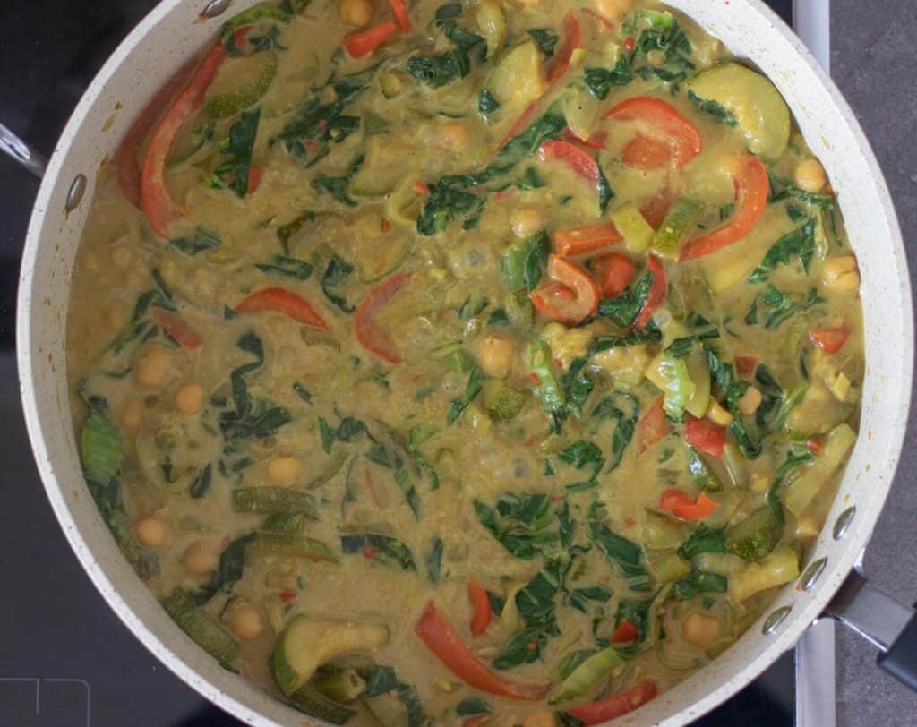 Cooked coconut curry with vegetables in a pan.