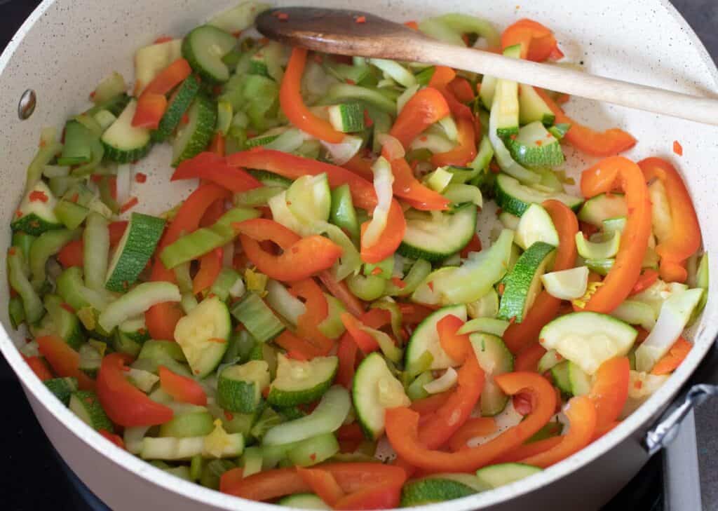 Cooked zucchini, red bell pepper, and bok choy in a pan.