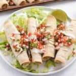 refried bean taquitos on a plate with lettuce and Pico de Gallo