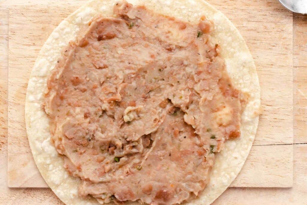refried beans spread out on a tortilla