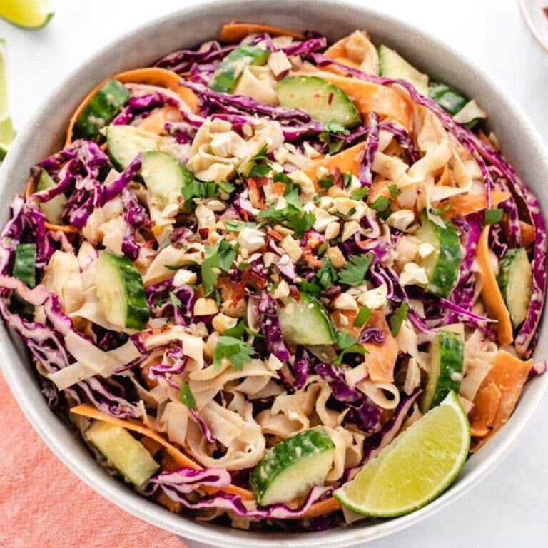 Peanut noodles with vegetables and a lime wedge.