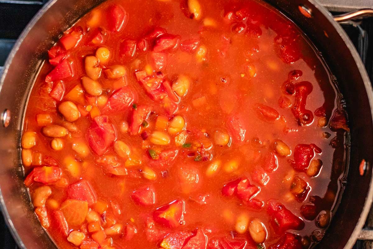 Lentil chili with pinto beans in a large pot with tomatoes.