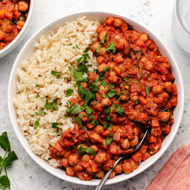 Tomato chickpea stew with rice in a bowl with a spoon.
