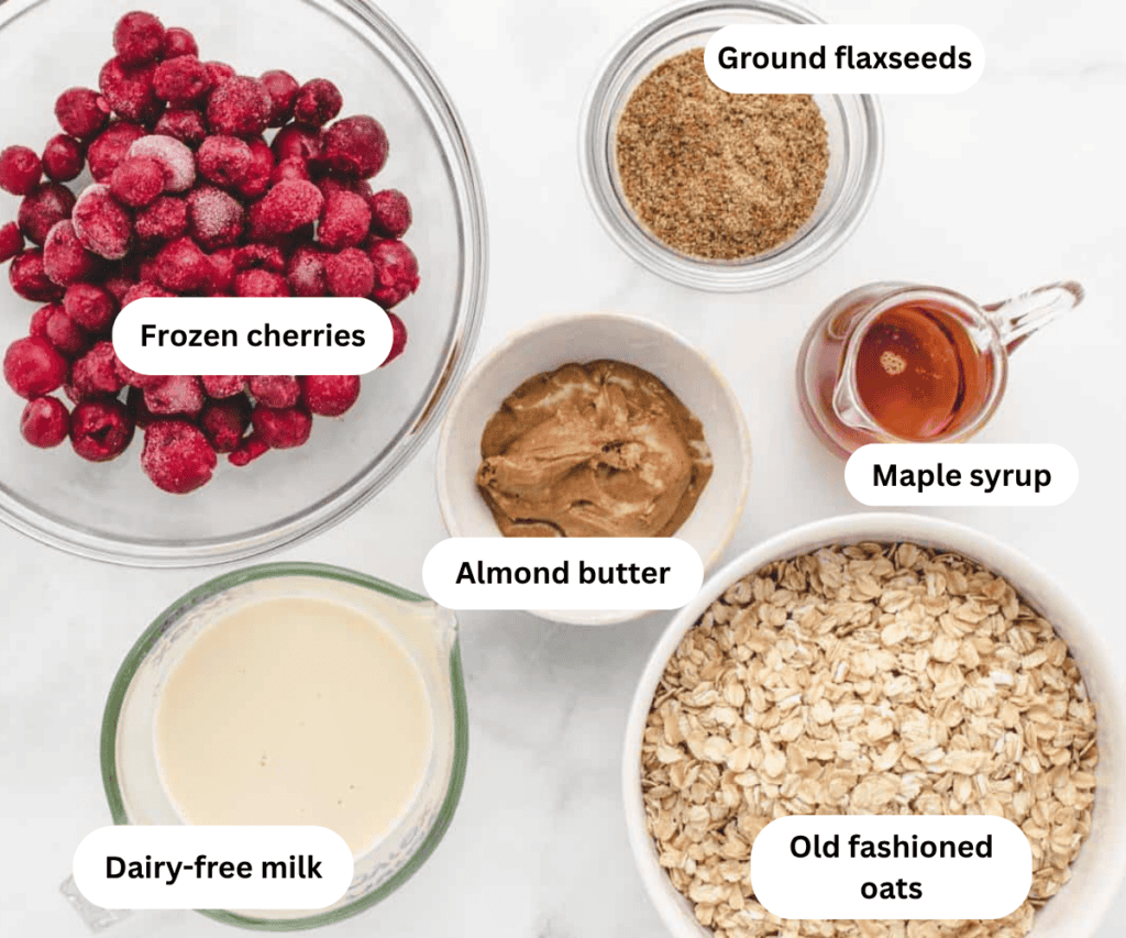 Frozen cherries, ground flaxseeds, dairy-free milk, almond butter, maple syrup, and rolled oats in bowls.