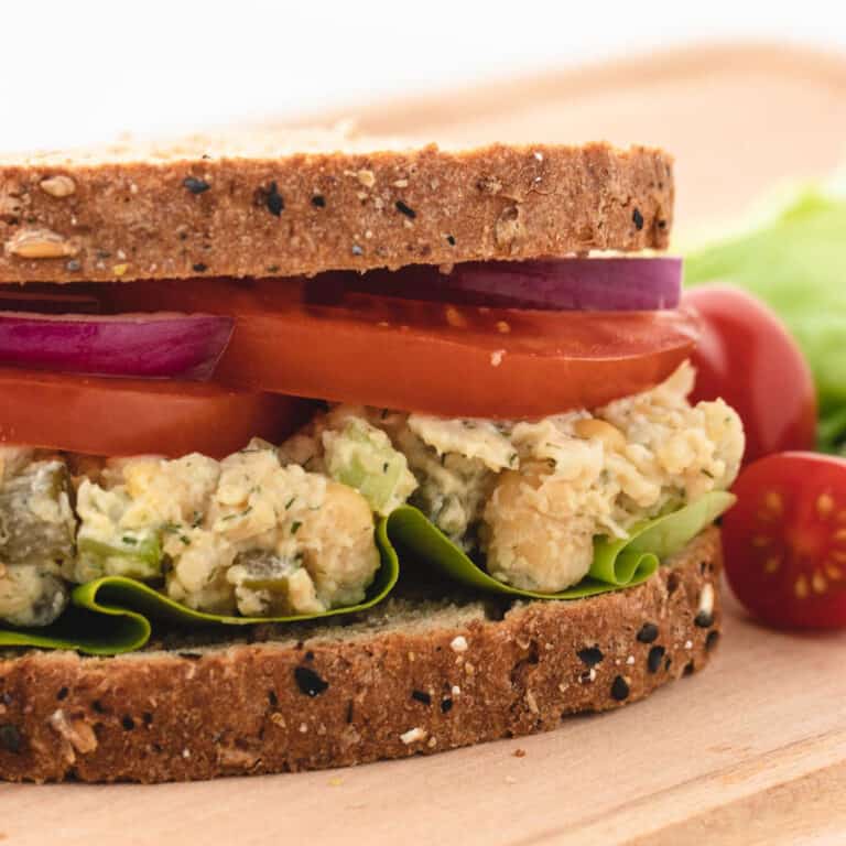 Vegan chickpea salad sandwich with tomatoes and red onion.