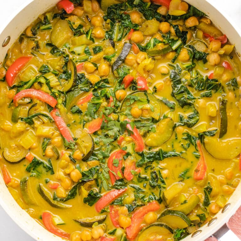 Vegan yellow curry with chickpeas and zucchini in large saute pan.