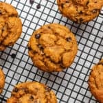 Vegan oil free pumpkin muffins on a cooling rack with chocolate chips.