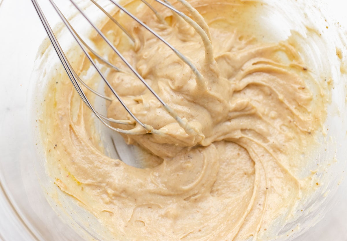 Tahini dressing in a glass bowl being mixed together.