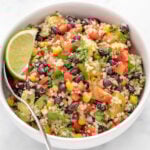 Zesty quinoa salad in bowl with a lime wedge.