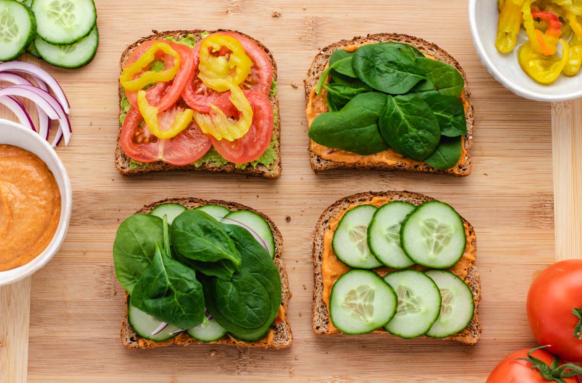 Open-face hummus cucumber sandwiches on a cutting board.