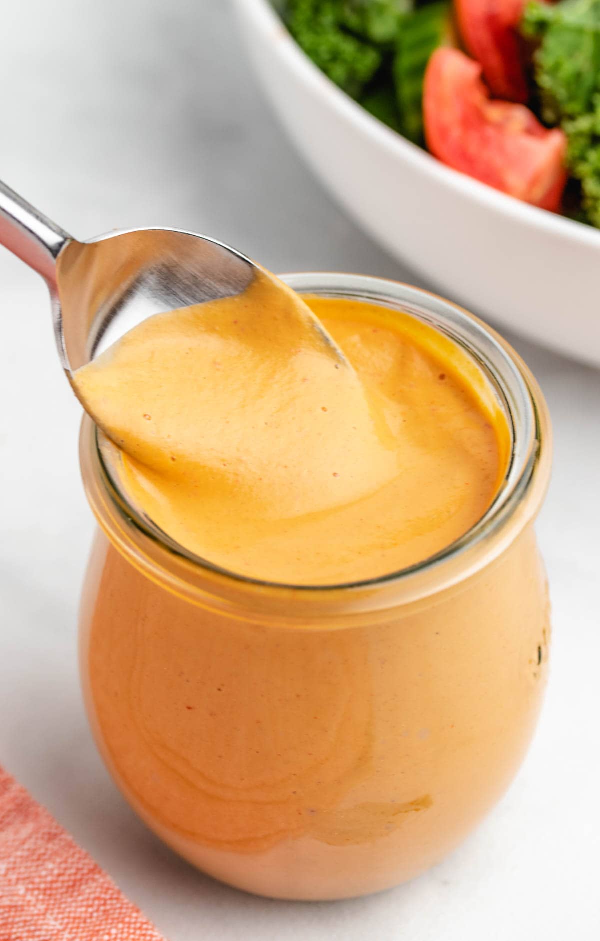 Vegan chipotle sauce in a glass jar with a spoon.