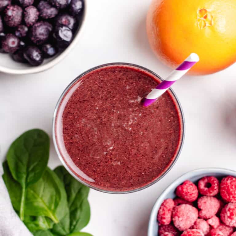 Bluberry and raspberry smoothie in glass with a straw.