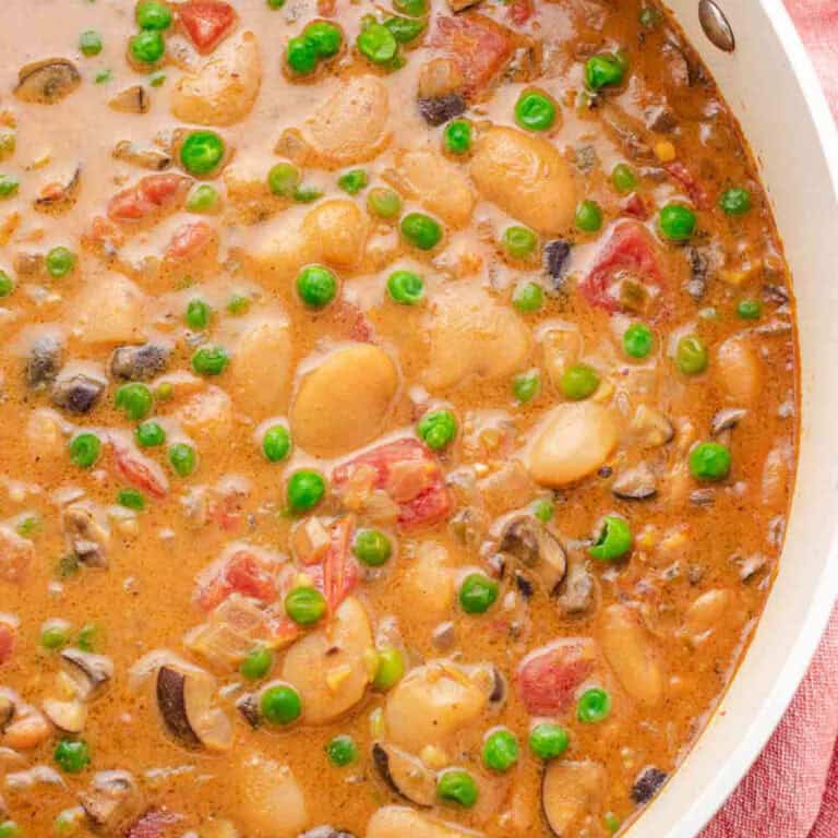 Butter bean curry with peas in a pan.