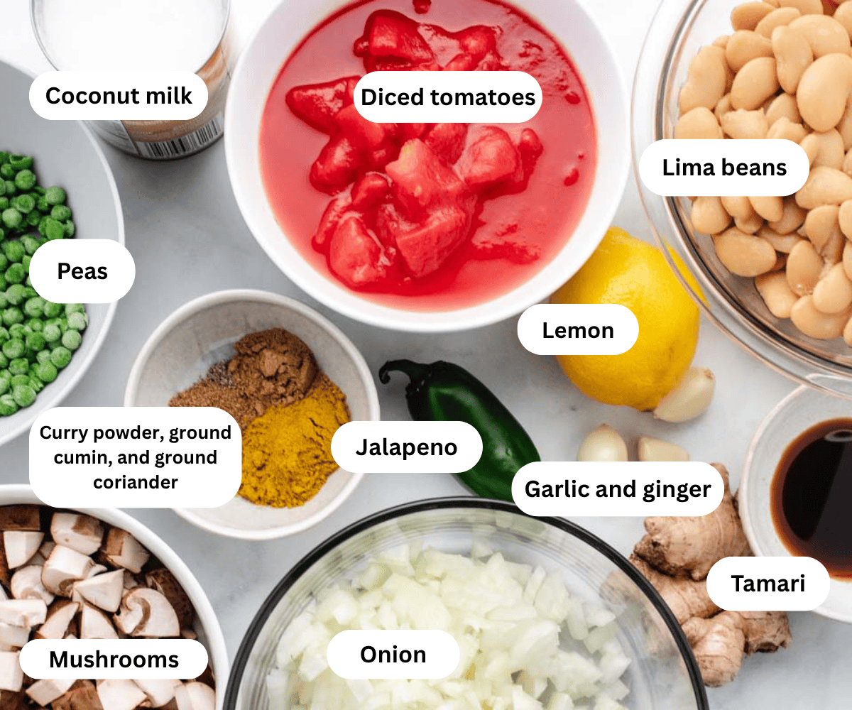 Coconut milk, diced tomatoes, lima beans, peas, mushrooms, spices, jalapeno, lemon, ginger, garlic, and onion in bowls.