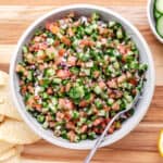 Cucumber pico de gallo in a bowl with chips to the side.
