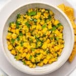 Mango corn salsa in a bowl with chopped cilantro on top.