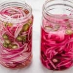 Two jars of spicy pickled red onions with jalapeños.