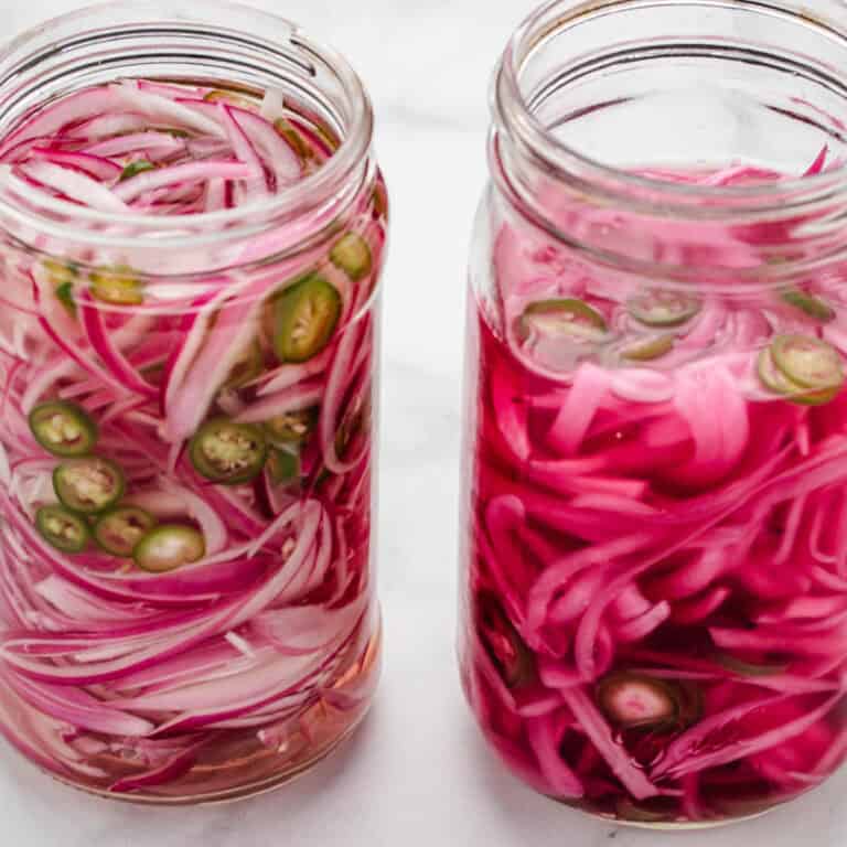 Two jars of spicy pickled red onions with jalapeños.