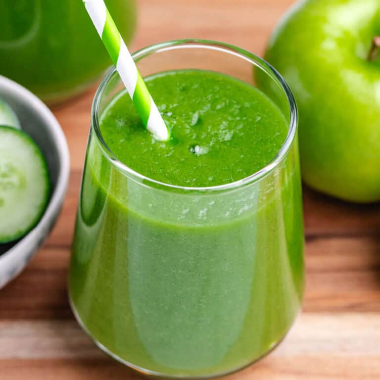 Apple cucumber green smoothie in a glass with a straw.