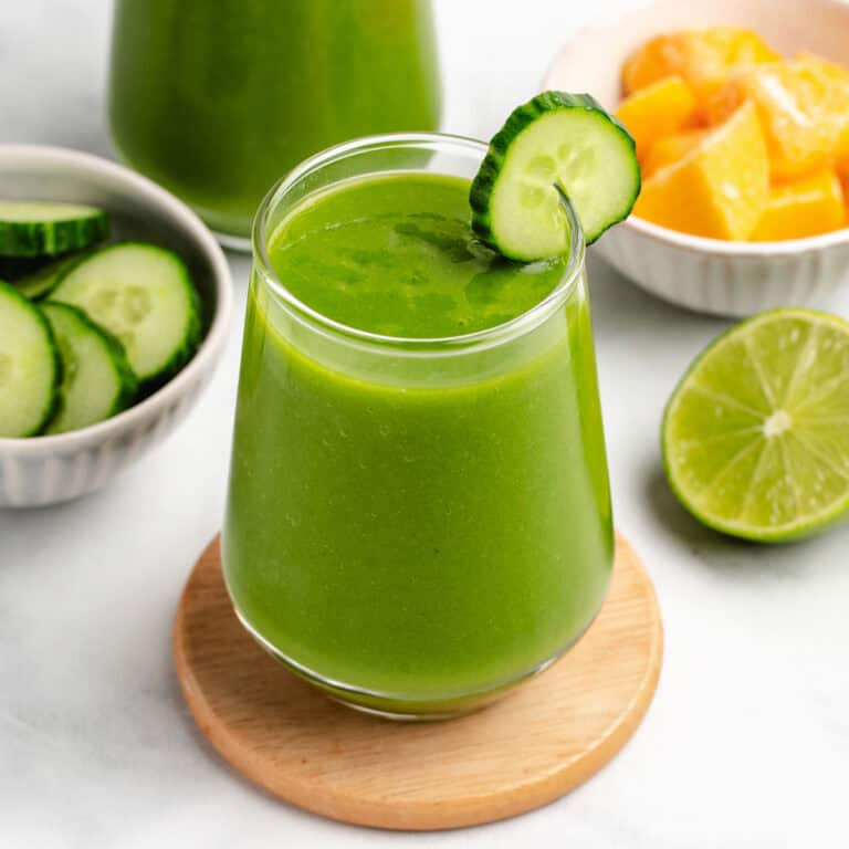 Mango cucumber smoothie in a glass with cucumber slice.