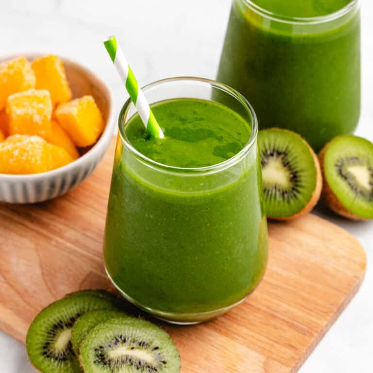 Kiwi mango green smoothie in a glass with a straw.
