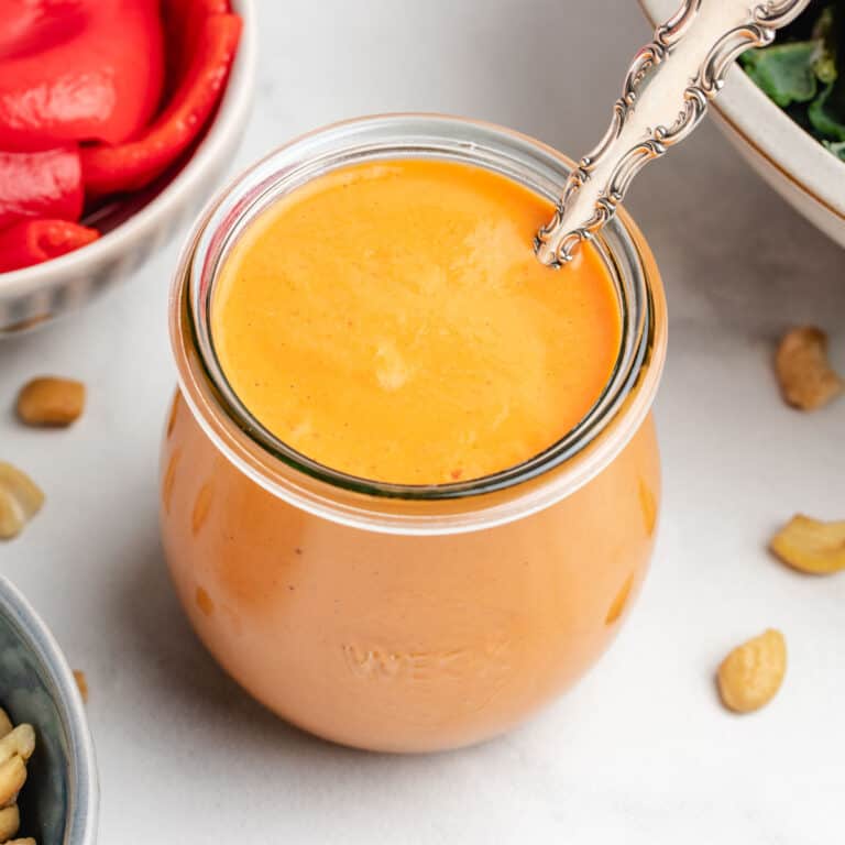 Roasted red pepper dressing in a glass with a spoon.