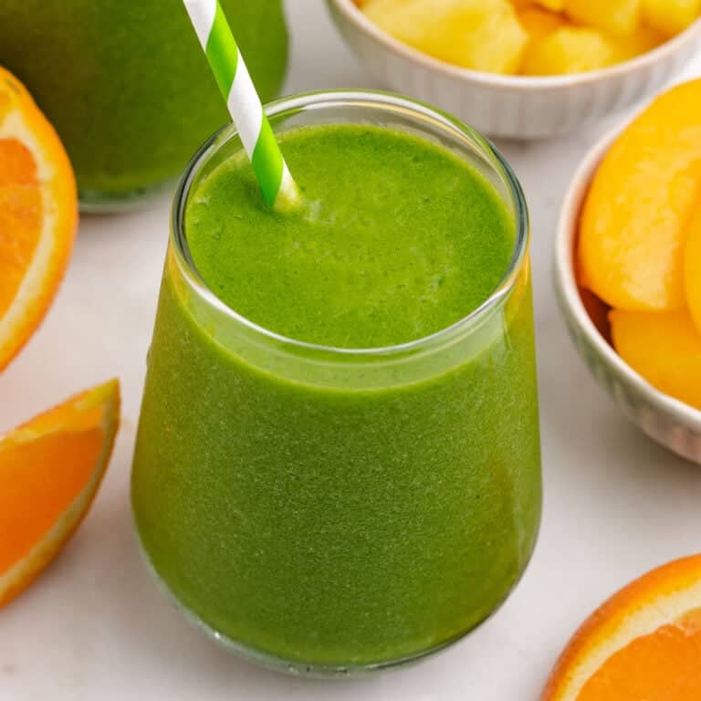 Peach pineapple smoothie in a glass with a straw.