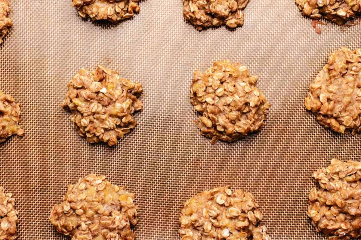 Baked banana walnut cookies on a silicone mat on a baking tray.