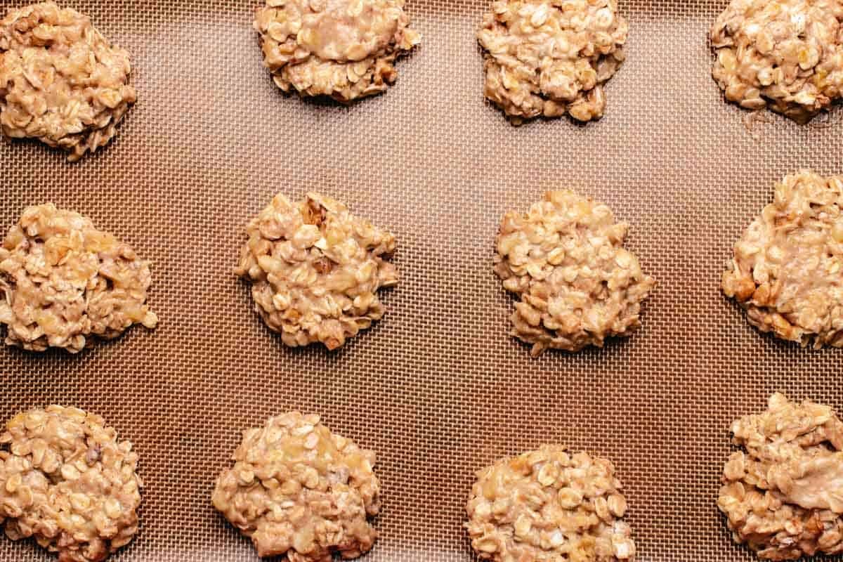 Uncooked oatmeal banana cookies in a baking tray with a silicone mat.