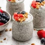 Yogurt chia seed pudding in a glass jar with granola, diced strawberries, and blueberries.
