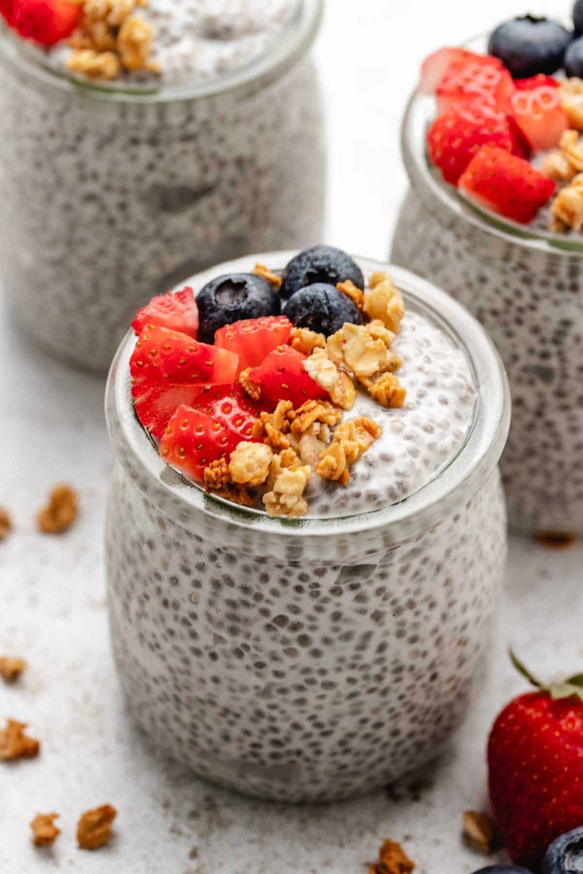 Chia yogurt pudding in a glass jar with diced strawberries, blueberries, and granola.