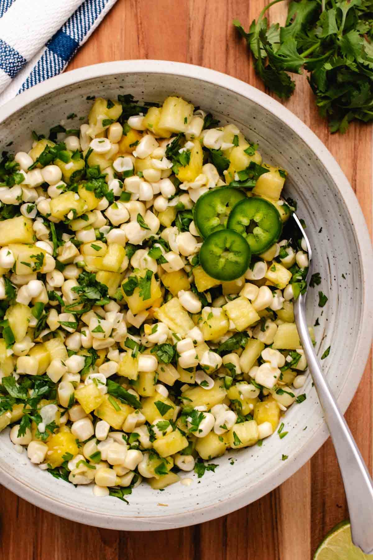 Corn pineapple salsa in a bowl with sliced jalapeno.