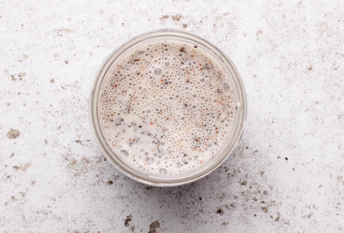 Dairy-free milk, dairy-free yogurt, maple syrup, and chia seeds mixed together in a jar.