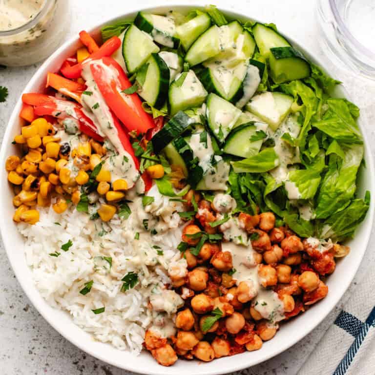 Chickpea bowl with tahini lime dressing, corn, rice, cucumbers, red bell peppers, and romaine lettuce.