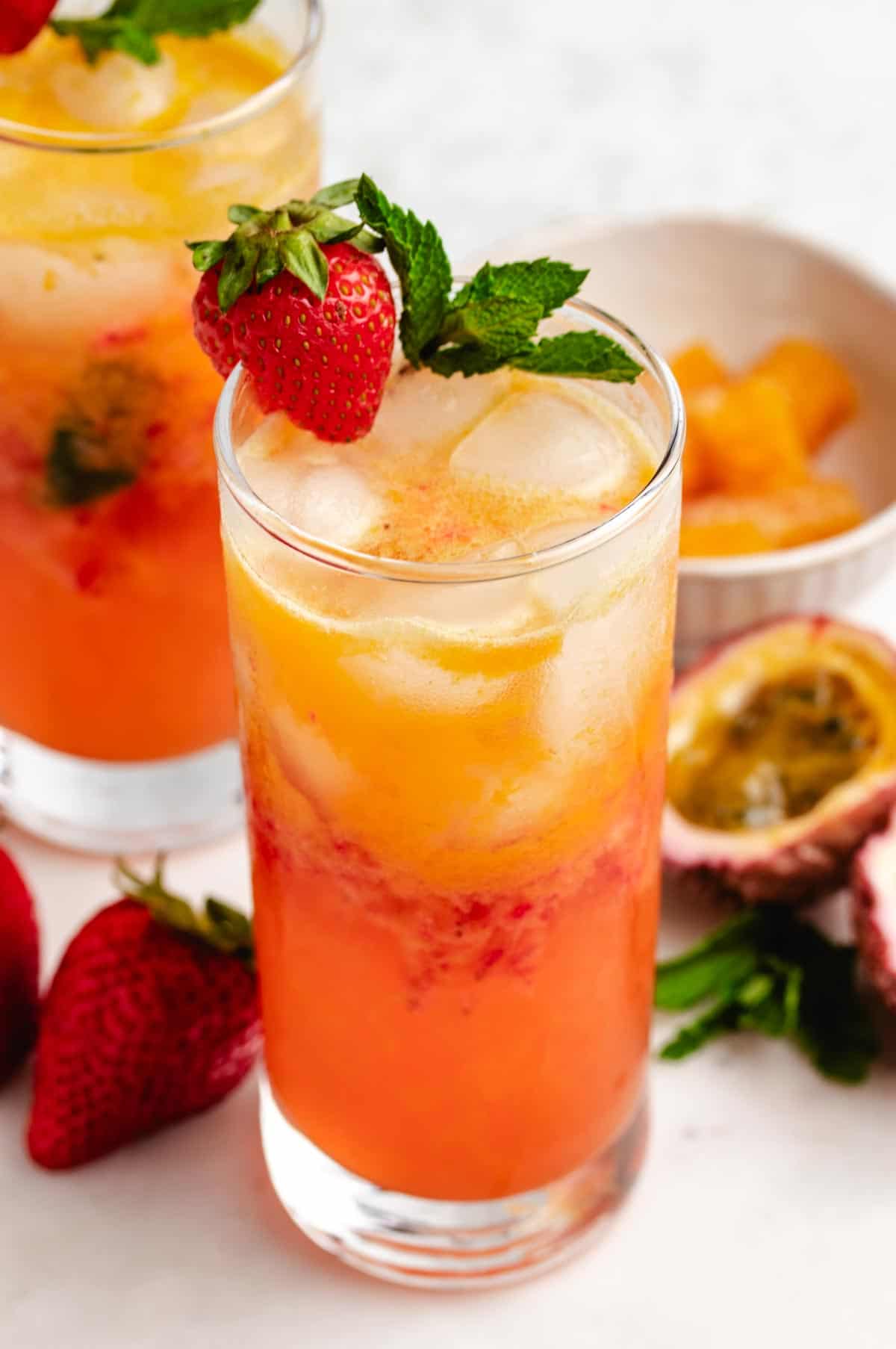 Passion fruit mocktails in glasses with a strawberry and mint leaves.