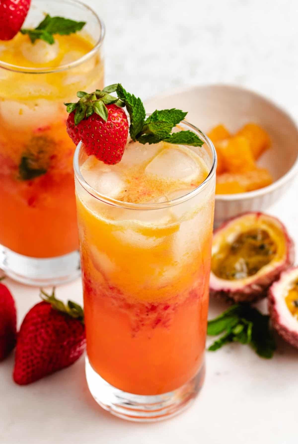 Mocktail with passion fruit in a glass with a strawberry and mint leaves.