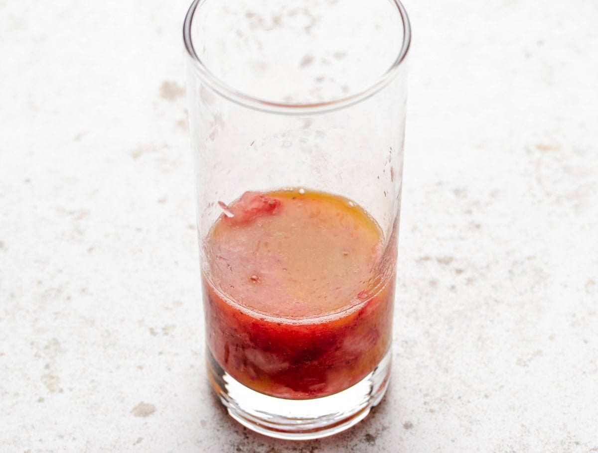 A glass of mashed strawberries and thawed passion fruit puree.