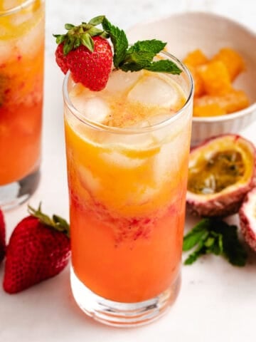 Passion fruit mocktail in a glass with a fresh strawberry and mint leaves.