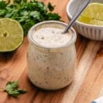 Tahini lime dressing in a jar with a spoon.